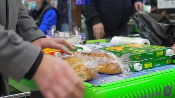 Mogilev ベラルーシ 2022年1月2日 スーパーマーケット 男はレジのテープに商品をレイアウトします モールや店舗での食料品の購入 — ストック動画