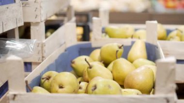 Woman picks up pears in store. Shopping concept, sale. Close-up of woman's hand, she takes pears from wooden box at grocery store. Healthy organic food and lifestyle concept