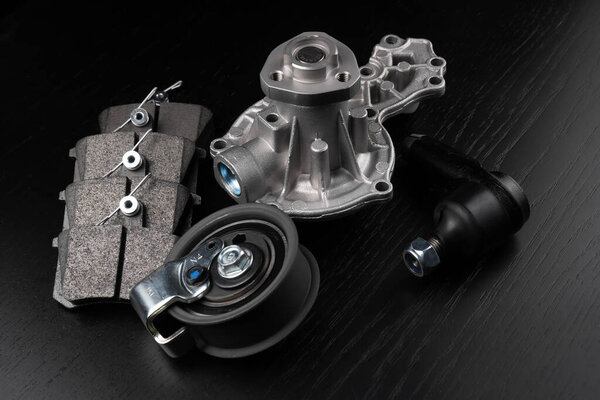 Закрыть автозапчасти автомобиля на черном фоне. Магазин автозапчастей. Подвеска и детали двигателя.