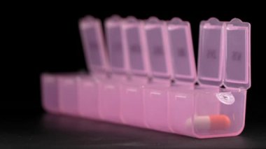Woman's hand puts pills for week in pill dispenser. Concept of health care and medicines. course of treatment for week. . Storing scheduled doses of medications in box.