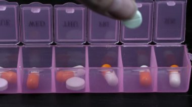 Woman's hand puts pills for week in pill dispenser. Concept of health care and medicines. course of treatment for week. . Storing scheduled doses of medications in box.