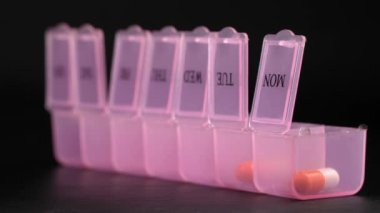 Woman's hand puts pills for week in pill dispenser. Concept of health care and medicines. course of treatment for week. . Storing scheduled doses of medications in box.