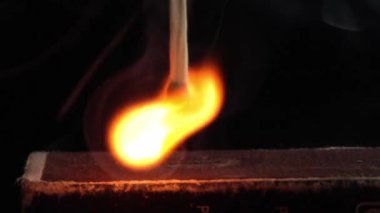 Matchstick light up after hitting flint surface of matchbox. Everything is real, no flame filters. Match moves on side of matchbox and light fire. Macro photography. slow motion.