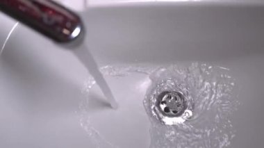 Close-up stainless steel sink hole filled with water. Water pours from water tap, but water drain does not cope and congestion is formed. Wastewater, assistance in case of plumbing breakdown.