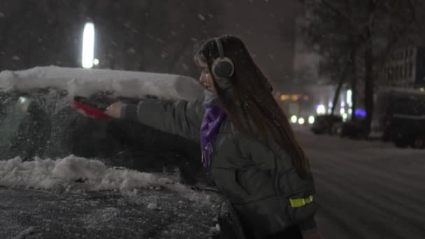 Young Girl Headphones Hat Listens Music Removes Snow Brush Car — Video