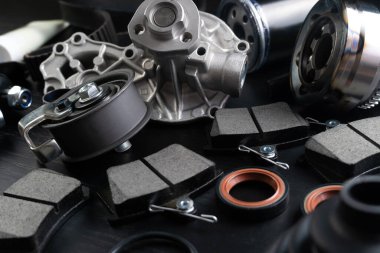 Otomobil parçalarının çoğu ahşap siyah arka planda yatıyor. Motor ve süspansiyon parçaları, döner eklem, eklem ve motor parçaları açıldı. Yeni yedek parça. Yön. Işıkla oyna. Masada asılı duruyor..