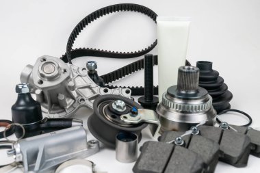 Birçok oto yedek parça beyaz arka planda yatıyor. Motor ve süspansiyon parçaları, döner eklem, eklem ve motor parçaları açıldı. Yeni yedek parça. Yön. Işıkla oyna. Masada asılı duruyor..