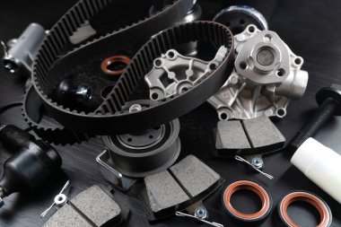 Otomobil parçalarının çoğu ahşap siyah arka planda yatıyor. Motor ve süspansiyon parçaları, döner eklem, eklem ve motor parçaları açıldı. Yeni yedek parça. Yön. Işıkla oyna. Masada asılı duruyor..