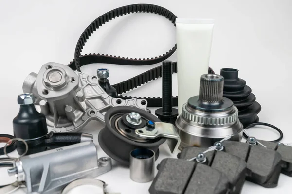 Birçok oto yedek parça beyaz arka planda yatıyor. Motor ve süspansiyon parçaları, döner eklem, eklem ve motor parçaları açıldı. Yeni yedek parça. Yön. Işıkla oyna. Masada asılı duruyor..