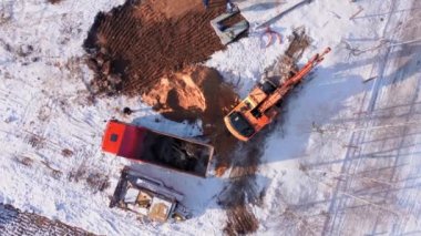 Toprak taşıma ekipmanları. Toprak taşıma makineleri ve çöp kamyonları olan büyük bir inşaat alanının havadan görüntüsü. Ağır makineler çalışıyor. Kazıcı kamyonu taşla dolduruyor. geliştirme karmaşık şehir.