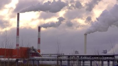 Kış endüstriyel manzarası. Kömürle çalışan elektrik santrali dramatik günbatımı gökyüzüne karşı bacalar tütütüyor. Şehirdeki hava kirliliği. Küresel iklim değişikliğinin birincil nedeni olarak karbondioksit CO2 emisyonları
