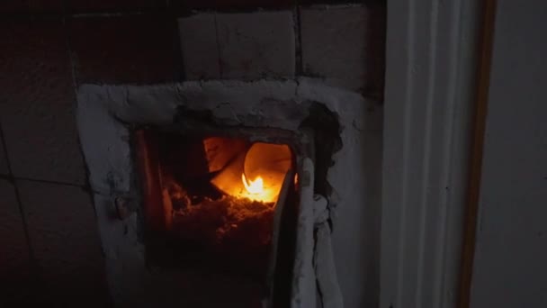 高齢者のカブス男は寒さから逃れるために古い村の家でストーブを溶かす ロシアだ 冷たくガスのない オーブンで薪で加熱する季節 田舎の家 — ストック動画