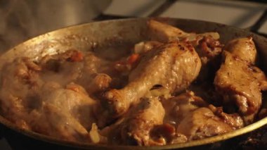 Tasty chicken meat portions in pan. Frying or roasting processing. Preparing food on kitchen stove. Drumstick and chicken legs are fried in slow motion.
