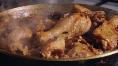 Tasty chicken meat portions in pan. Frying or roasting processing. Preparing food on kitchen stove. Drumstick and chicken legs are fried in slow motion.