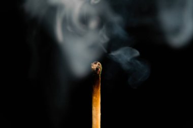 Siyah arka planda dumanla aydınlatılmış bir kibrit, makro fotoğraf. Dumanla sönmüş bir kibrit.