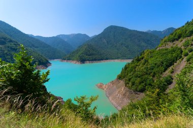 Inguri Nehri 'ndeki Jvari rezervuarı. Güneşli bir günde güzel bir dağ manzarası. Kafkas sıradağlarıyla çevrili turkuaz sularla dolu bir göl. Georgia, Svaneti