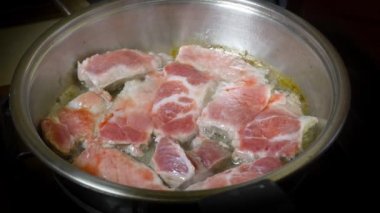 Yakından, kızgın yağda kavrulmuş et, dökme demir tavada kızartılıyor. Kızarmış pastırma dilimleri. Kızartma tavasında sulu et. Kızarmış biftek pişirme işlemi.