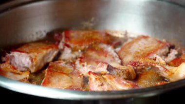 Yakından, kızgın yağda kavrulmuş et, dökme demir tavada kızartılıyor. Kızarmış pastırma dilimleri. Kızartma tavasında sulu et. Kızarmış biftek pişirme işlemi.