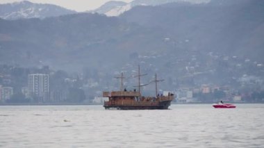 Gürcistan 'ın Karadeniz kıyısındaki Batumi körfezindeki dağ peronlarına karşı denizde yelken açan Retro-style turist eğlence gemisi. Gemide bir sürü turist var, eğleniyorlar ve güzelliğe hayranlar..