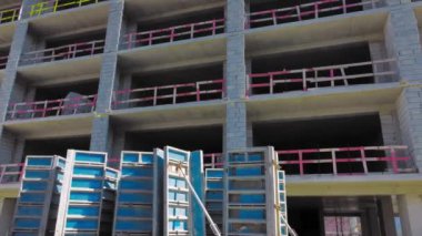 Mavi gökyüzüne karşı yeni tamamlanmamış uzun apartman kompleksi, etrafta uçuşuyor ve yükseklikten drone görüşü. Müteahhitlerin gayrimenkul anlaşması. Inevestia 'dan geleceğe. Güçlendirilmiş beton bina.