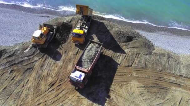 ジョージア州バトゥミ 2023年 トラックをダンプし 堤防や海岸を修復し 強化し 海や海に土壌や砂をアンロードします ドローンからの眺め ブルドーザーは海岸を増やすために地球で海岸を埋めます — ストック動画