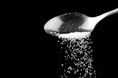 Siyah zemin üzerinde ufalanan beyaz şekerli çay kaşığının makro fotoğrafçılığı, boşluğu kopyala.