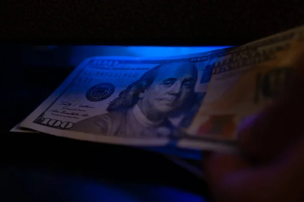 Close-up of dollars under an ultraviolet lamp. Inspection of a dollar bill using a money detector.