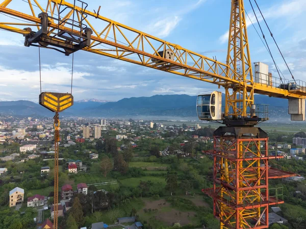 stock image Close-up view from a drone of a construction crane cabin against the backdrop of beautiful mountains and sky. Construction concept