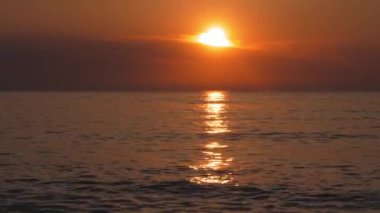Gün batımlı sakin deniz, bulutların arasından gökyüzü ve güneş. Okyanus ve Gökyüzü Arkaplan Meditasyonu. Huzurlu deniz manzarası. Ufuk suyun üstünde. deniz manzaralı gökyüzü arkaplanı