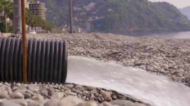 Su, drenaj borusundan yeraltı suyuna akar. Palmiye ağaçları ve mavi gökyüzü için taksi inşaatı enkazı. Çevre kirliliği: dağlar ve deniz.