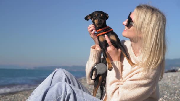 Mulher Sentada Praia Por Mar Dia Ensolarado Segurando Pequeno Cão — Vídeo de Stock