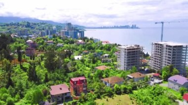İnsansız hava aracı deniz kıyısında hareket ettiğinde. Gayrimenkulleri ön plana çıkarıyor. İnşaata yatırım. Georgia mı? Karadeniz. Makhinjauri. Arka planda yeşil yüksek dağlar var. Batum 'un Kenar Mahallesi.