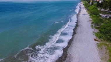 Deniz ya da okyanus dalgaları çakıl taşı plajına çarpıyor. Drone 'un yukarıdan görüntüsü. Güneşli ve sıcak bir günde sahilde. Tatil köyü veya Kurotnaya bölgesi.