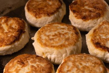 Kızartma tavasında kızartılmış süzme peynirli kekleri yakından çek. Lezzetli ev yemekleri pişirme süreci.