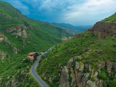 Küçük bir lokantası olan dağların insansız hava aracı manzarası. Dağlarda bir yolu olan güzel bir manzara. Seyahat