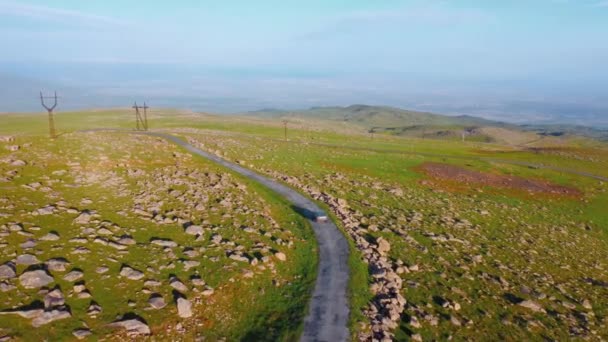 車は道路に沿って移動し アルメニアの山の中で道を高くしています ドローン写真は壮大な風景を捉えます 無人機は車に従い 冒険の雰囲気を伝えます — ストック動画
