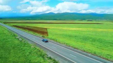 İnsansız hava aracı görüntüleri, nefes kesen dağlar ve pitoresk yeşil çayırlar arasında otoban olduğunu gösteriyor. Araba yol boyunca koşuyor, büyülü manzaralarla örtülü. Macera ve seyahat özgürlüğü anı