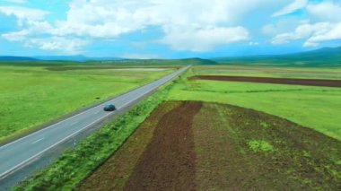 İnsansız hava aracı görüntüleri, nefes kesen dağlar ve pitoresk yeşil çayırlar arasında otoban olduğunu gösteriyor. Araba yol boyunca koşuyor, büyülü manzaralarla örtülü. Macera ve seyahat özgürlüğü anı