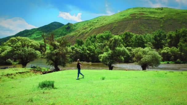 Молода Жінка Джинсах Футболці Гуляє Поблизу Гірської Річки Тлі Гір — стокове відео