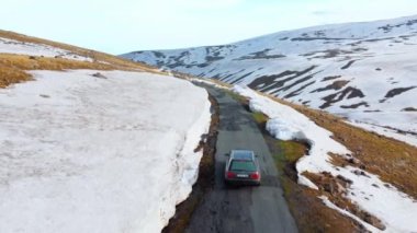 Ermenistan, Erivan - 2 Haziran 2023: Turistler karlı dağlara arabayla tırmandılar. Aragats Dağı, İHA karlı dağlarda giden arabayı takip ediyor. Güzel manzara