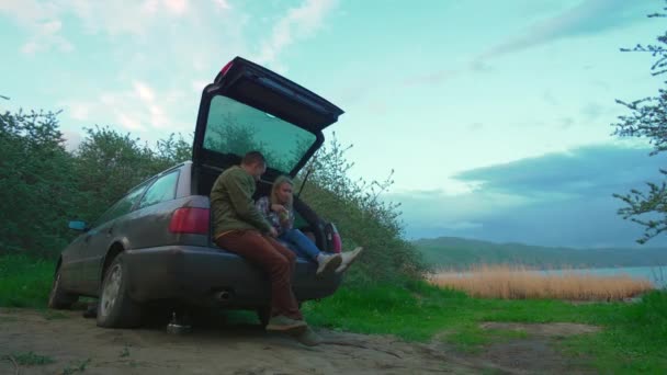 Młoda Para Podróży Mężczyzna Kobieta Siedzą Bagażniku Samochodu Jedzą Nad — Wideo stockowe
