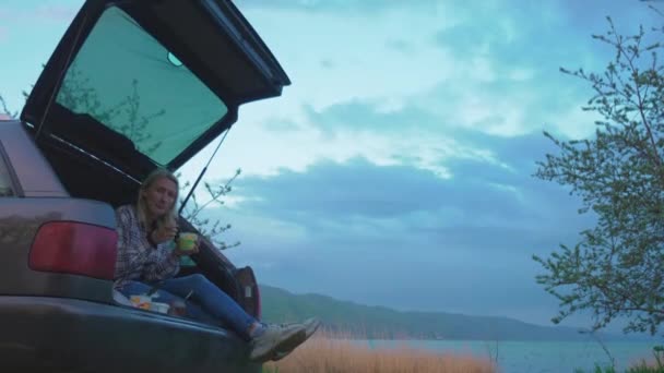 Młoda Para Podróży Kobieta Siedzieć Bagażniku Samochodu Jeść Nad Rzeką — Wideo stockowe