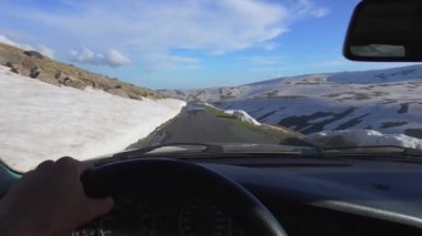Arabadan içeriden birinci şahıstan, karlı dağlarda yol manzarası. Şoförün elleri direksiyonda, kışın araba sürüyor. Ermenistan, Aragats Dağı. Şoförün eli direksiyonda. Seyahat