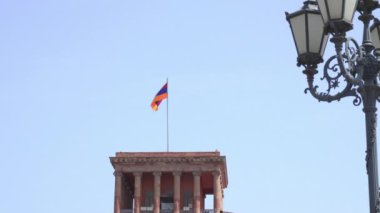 Erivan 'da başkentin ana meydanında Ermenistan bayrağı dalgalanıyor. Yazın güneşli bir günde, arka planda mavi gökyüzüne karşı inşa etmek.