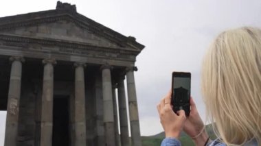 İyonik düzende Greko-Romen tarzında inşa edilen Garni Tapınağı, Ermenistan tarihinin turizm ve Hıristiyanlık öncesi döneminin başlıca simgesidir. Kadın akıllı telefon kamerasıyla fotoğraf çekiyor..