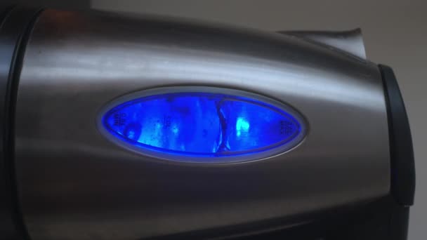 ネオンブルーの照明で沸騰水と電気ケトルの垂直ビデオ ケトルは暗い部屋で台所で沸騰している コーヒーや紅茶用のお湯や沸かし湯の準備 — ストック動画