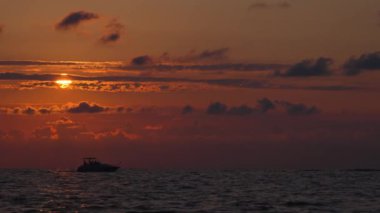 Gün batımında gökyüzü ve bulutların arasında güneş olan sakin bir deniz. Meditasyon okyanusu ve gökyüzü arka planı. Huzurlu deniz manzarası. Ufuk suya karşı. Arka planda gemi ya da yat yüzüyor.