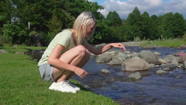 年轻美丽的布伦迪纳在山河中触摸水 女人在清澈的河里尿手或洗手 大自然的概念和其中的脉络 关心环境 — 图库视频影像