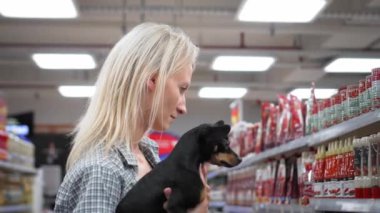 Küçük köpek oyuncak teriyeri ile genç güzel sarışın kadın süpermarkette ya da markette yürüyor ve alışveriş yapıyor. Aile, çocuklar için özgürlük. Çocuk Serbest