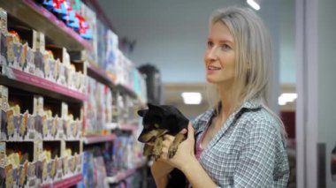 Küçük köpek oyuncak teriyeri ile genç güzel sarışın kadın süpermarkette ya da markette yürüyor ve alışveriş yapıyor. Aile, çocuklar için özgürlük. Çocuk Serbest